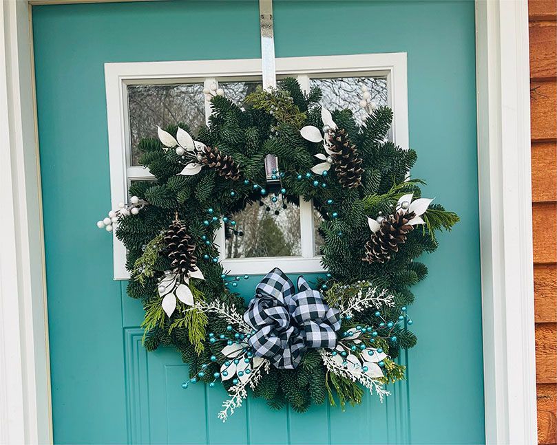 A christmas wreath is hanging on a blue door.