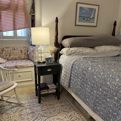 A bedroom with a bed , nightstand , chair and window seat.