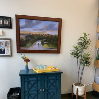 A painting is hanging on a wall above a blue cabinet.