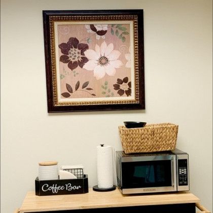A coffee bar with a microwave and a picture on the wall above it.