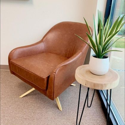 A brown leather chair is sitting next to a small table with a plant on it.