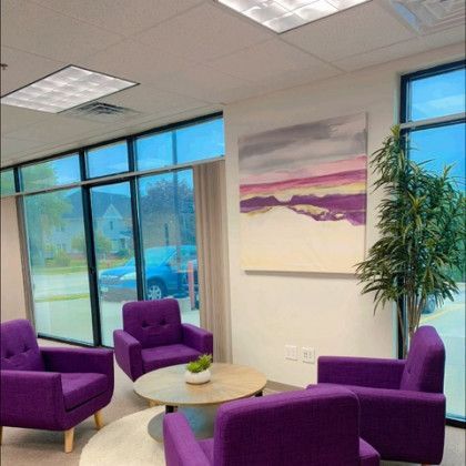 A living room with purple chairs and a painting on the wall