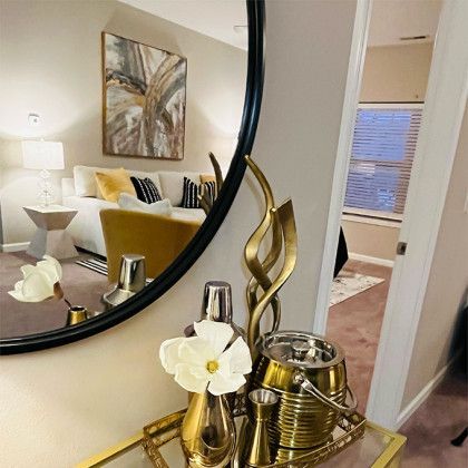 A living room with a round mirror and a table with flowers on it.