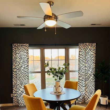 A dining room with a table and chairs and a ceiling fan.