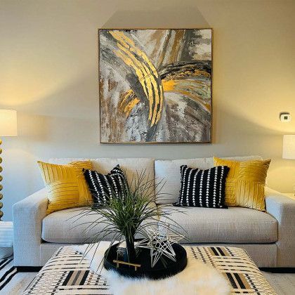 A living room with a couch , coffee table , and a painting on the wall.