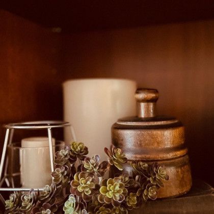 A wooden container with a lid is sitting on a shelf next to a candle and a plant.