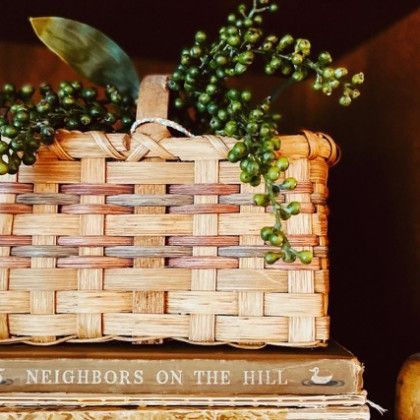 A basket sits on top of a stack of books titled neighbors on the hill
