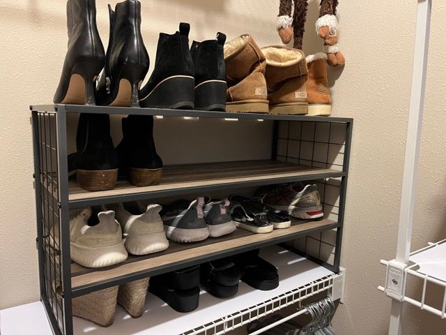 A shoe rack filled with shoes and boots in a closet.