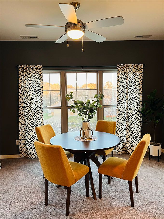 A dining room with a table and chairs and a ceiling fan.