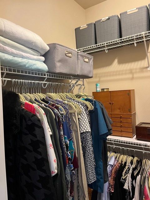 A closet filled with clothes and a stack of pillows