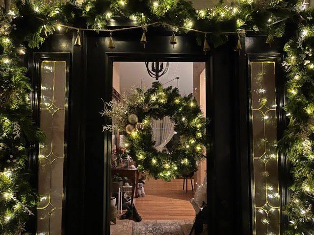A doorway decorated for christmas with a wreath and lights.