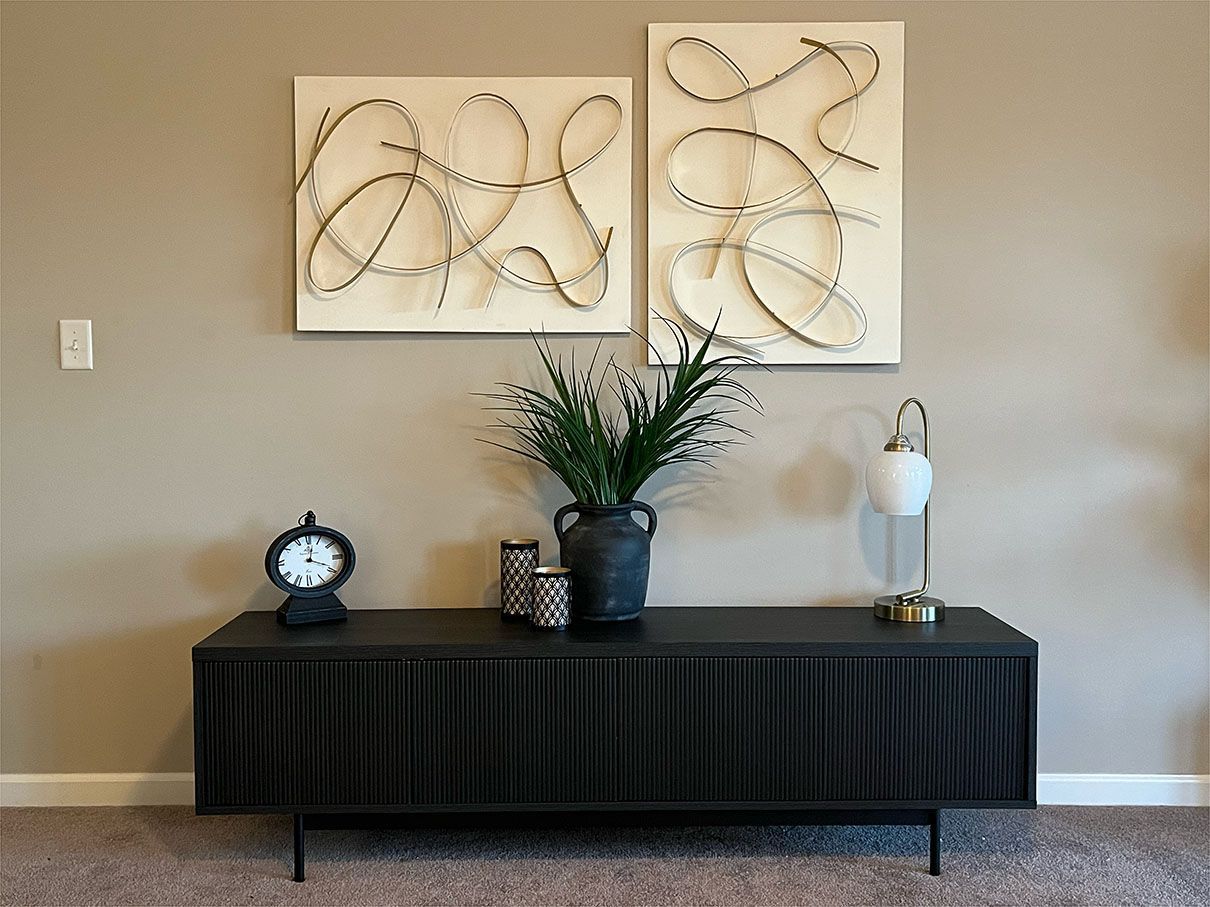 A living room with a black dresser and two paintings on the wall