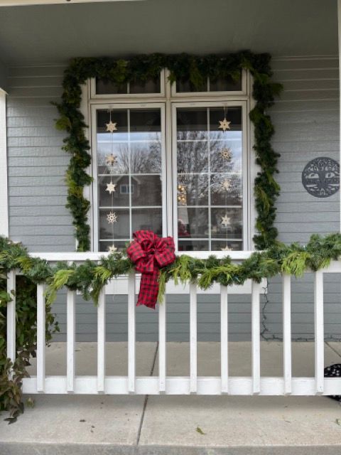 A porch decorated for christmas with a red bow