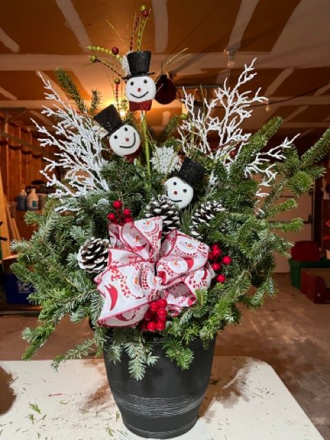 A black vase filled with christmas decorations and snowmen