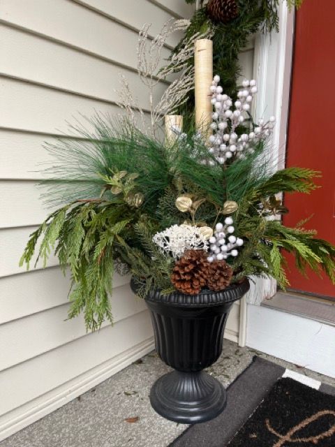 A black urn filled with pine cones and flowers