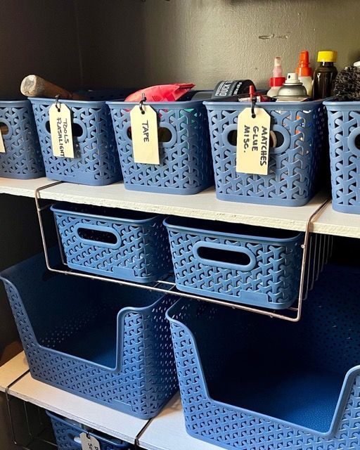 A shelf filled with blue baskets with tags on them.