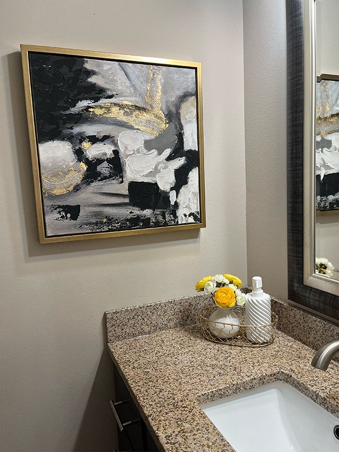 A bathroom with a sink and a painting on the wall above it.