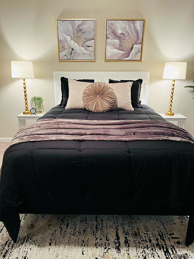 A bedroom with a bed , two nightstands , two lamps and two paintings on the wall.