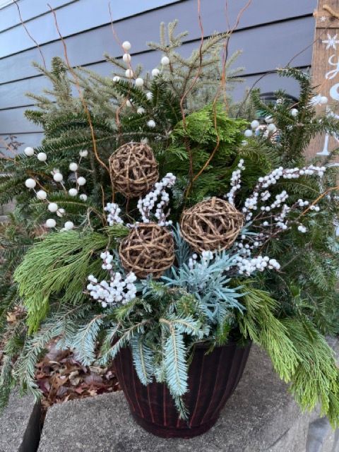 A pot filled with christmas decorations and plants is sitting on a table.