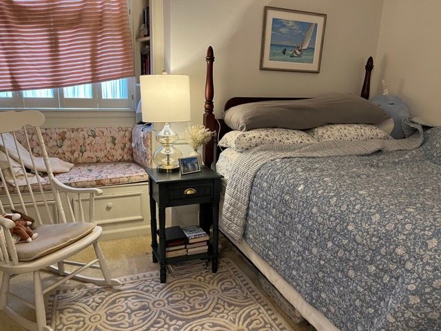 A bedroom with a bed and a rocking chair