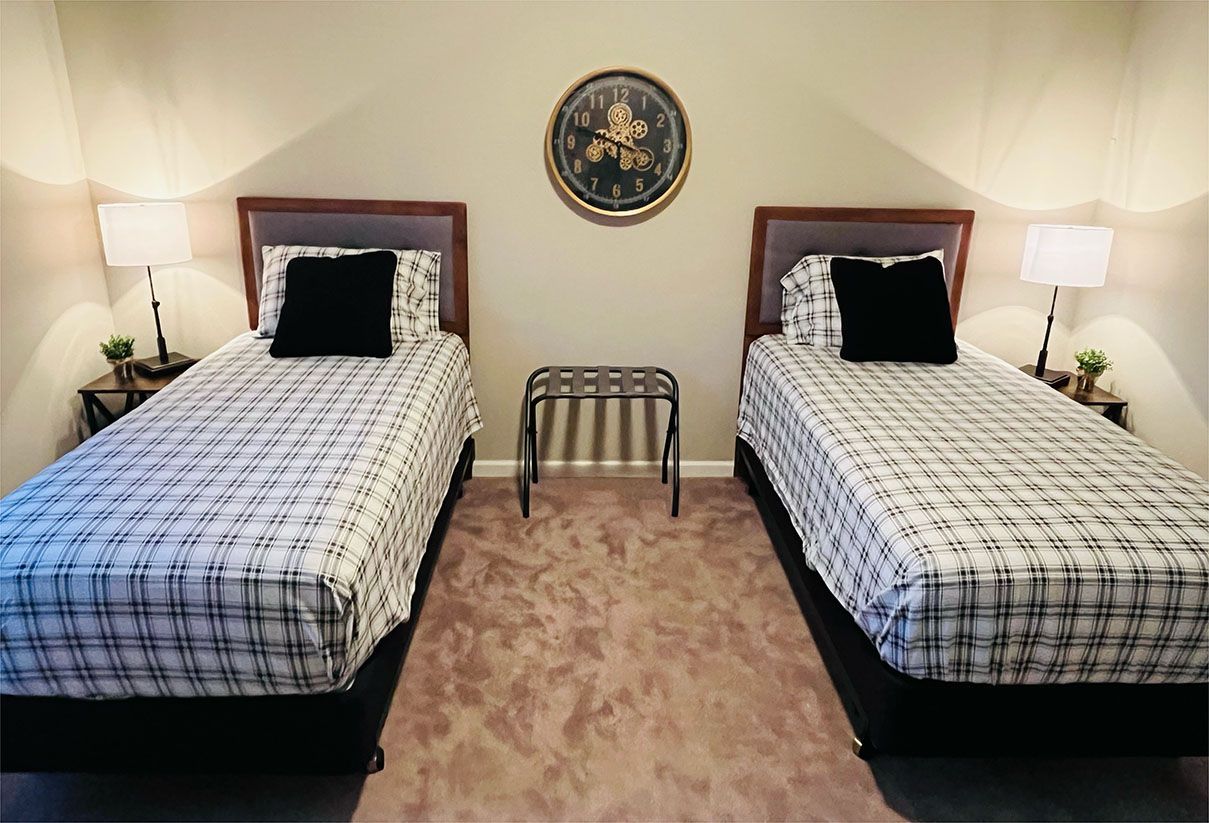 A bedroom with two twin beds and a clock on the wall.