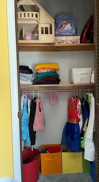 A closet filled with clothes and a doll house.