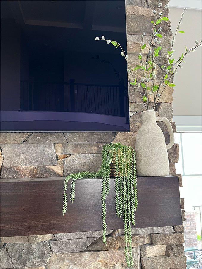 A fireplace with a flat screen tv and a vase on it.