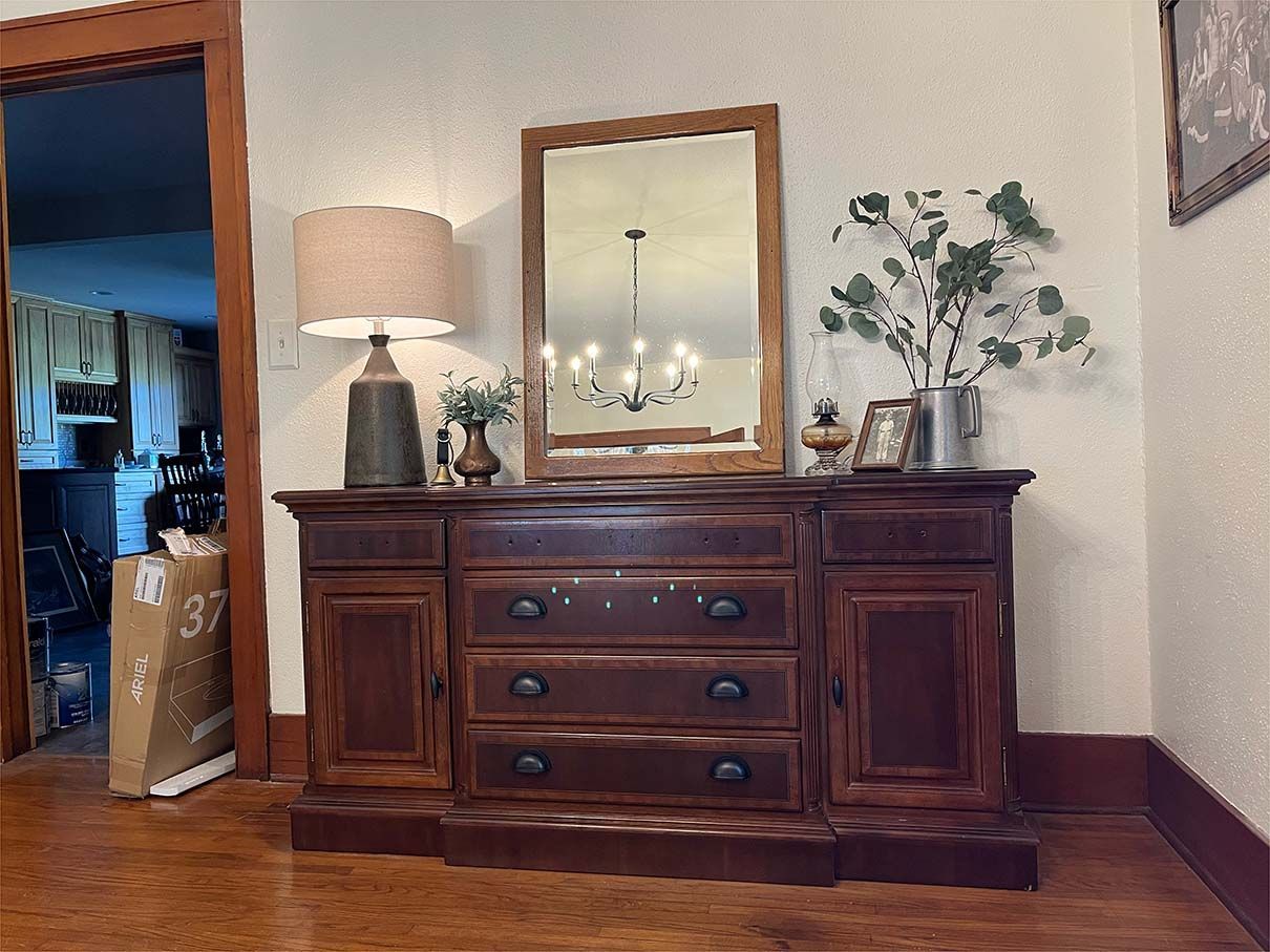 A wooden dresser with drawers and a mirror in a living room.