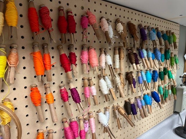 Spools of yarn are hanging on a peg board