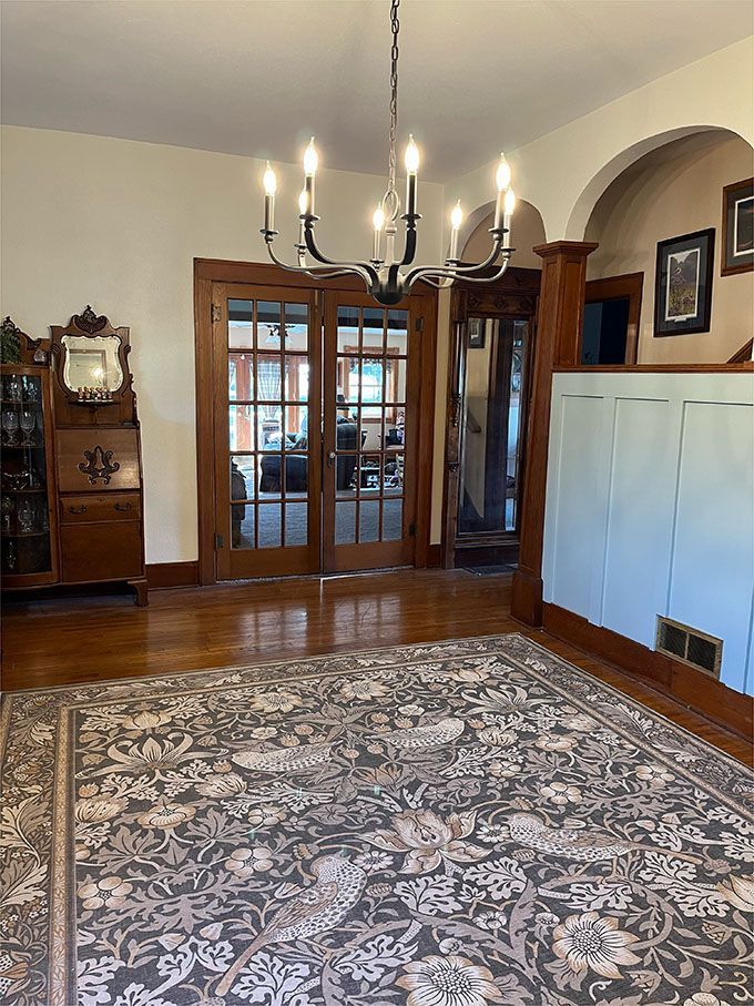 A living room with a rug and a chandelier.