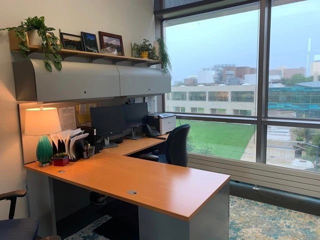 A small office with a desk , chair , computer and a large window.