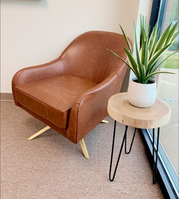 A brown chair is sitting next to a small table with a plant on it