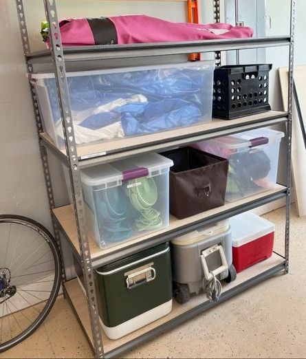 A shelf filled with boxes and coolers in a garage