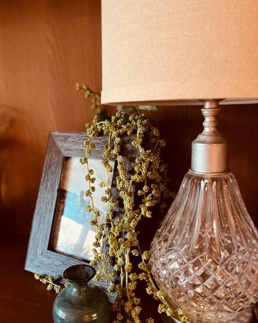 A lamp is sitting on a table next to a picture frame and a vase.