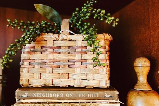 A wicker basket is sitting on top of a stack of books.