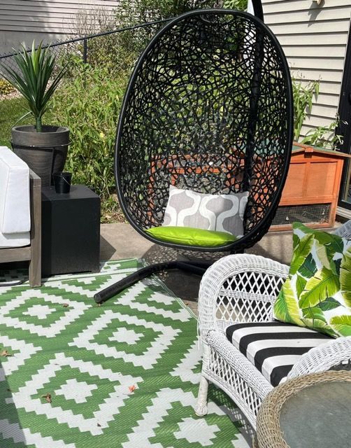 A hanging chair is sitting on a green and white rug