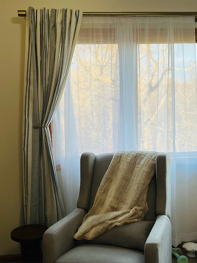 A chair with a blanket on it in front of a window