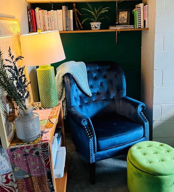 A living room with a blue chair and a green ottoman