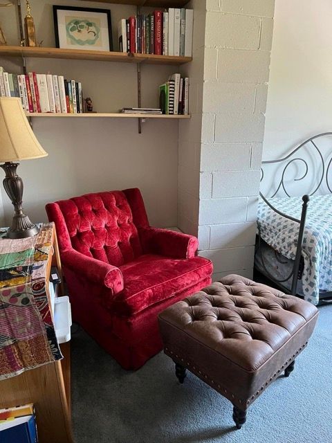 A bedroom with a red chair and an ottoman