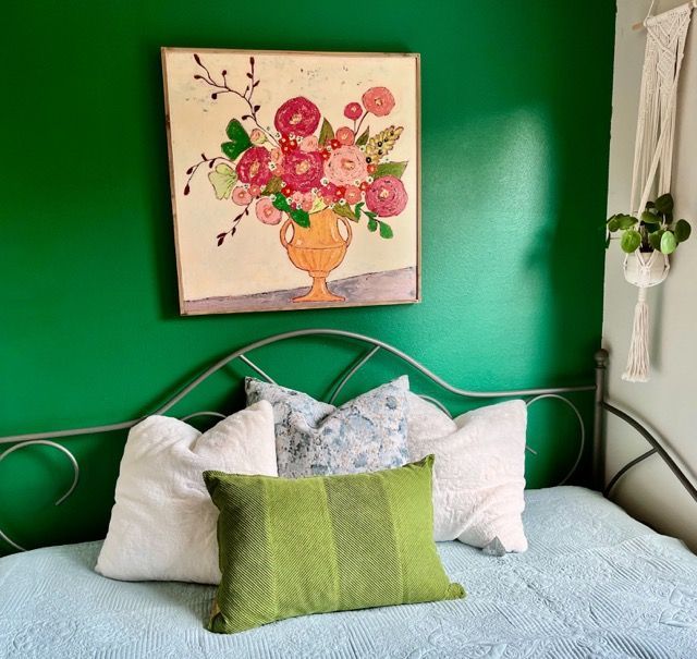 A bed with pillows and a painting on the wall above it