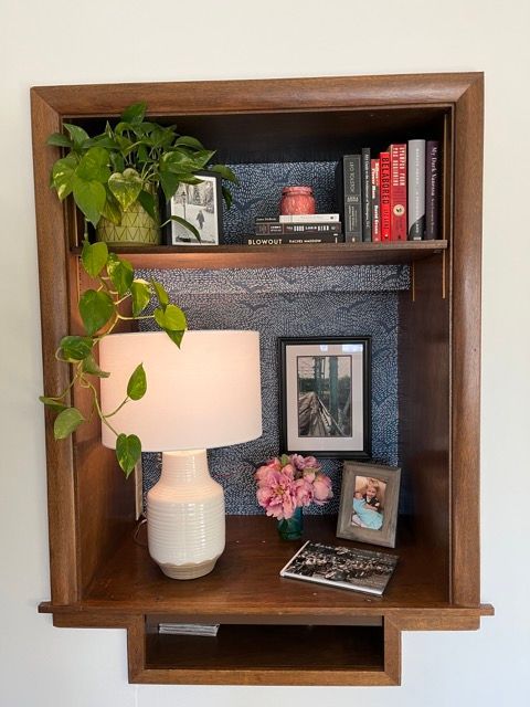 A shelf with a lamp flowers and books on it