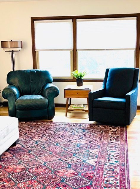 A living room with two chairs and a rug