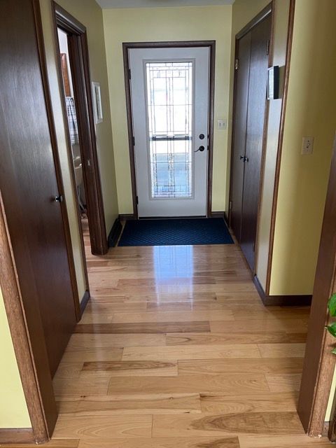A hallway with hardwood floors and a door in a house.