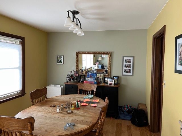 A dining room with a table and chairs and a mirror