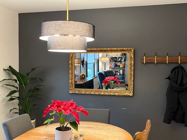 A dining room with a table and chairs and a mirror on the wall.