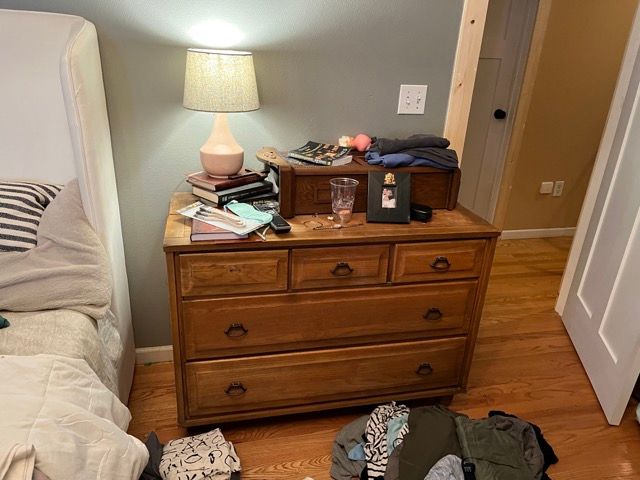 A bedroom with a dresser and a lamp on it