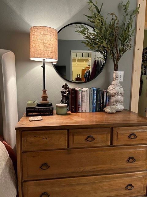 A wooden dresser with a lamp and books on it