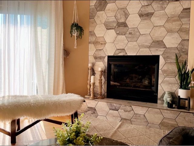 A living room with a fireplace surrounded by hexagonal tiles.