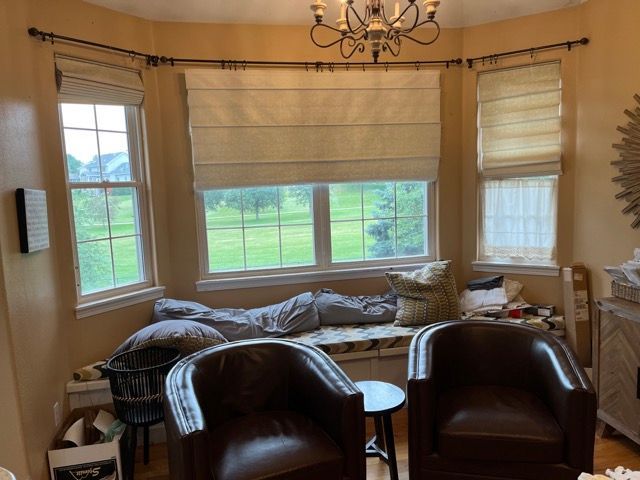 A living room with two chairs , a bench and a chandelier.