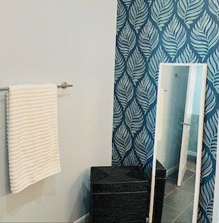 A bathroom with a full length mirror and a laundry basket.